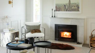 The cosy Christchurch home living room with the fire roaring beside a soft leather armchair