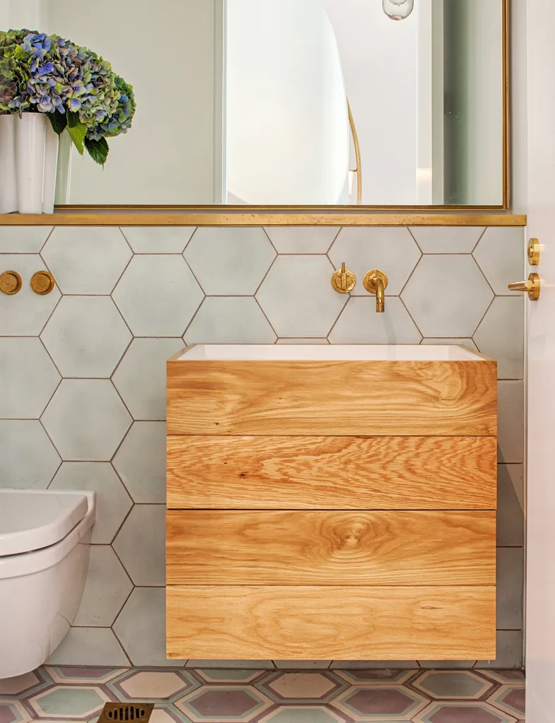 A timber vanity with hexagon blue tiles behind.