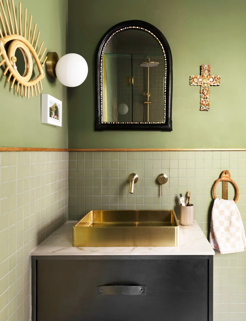 A green bathroom with a small vanity and bathroom mirror