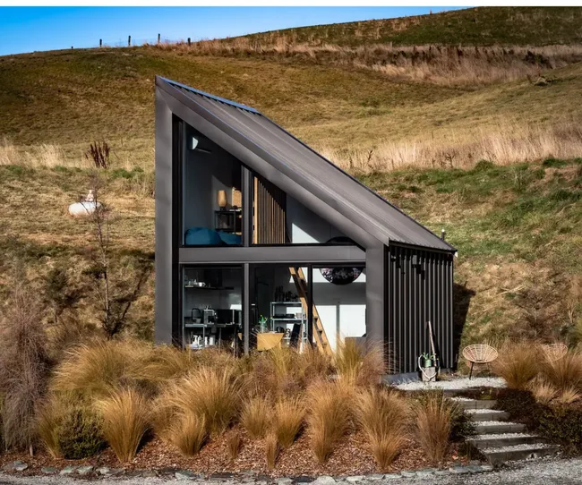 A black tiny house in a rural setting