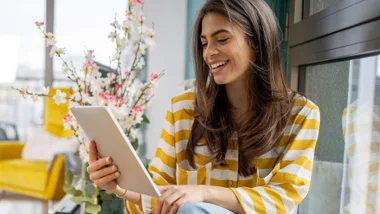 A woman siting on a couch playing with the best tech gadgets