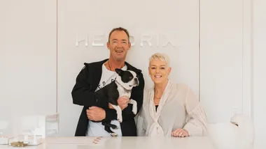 A man and a woman with a French bulldog standing in front of a white counter