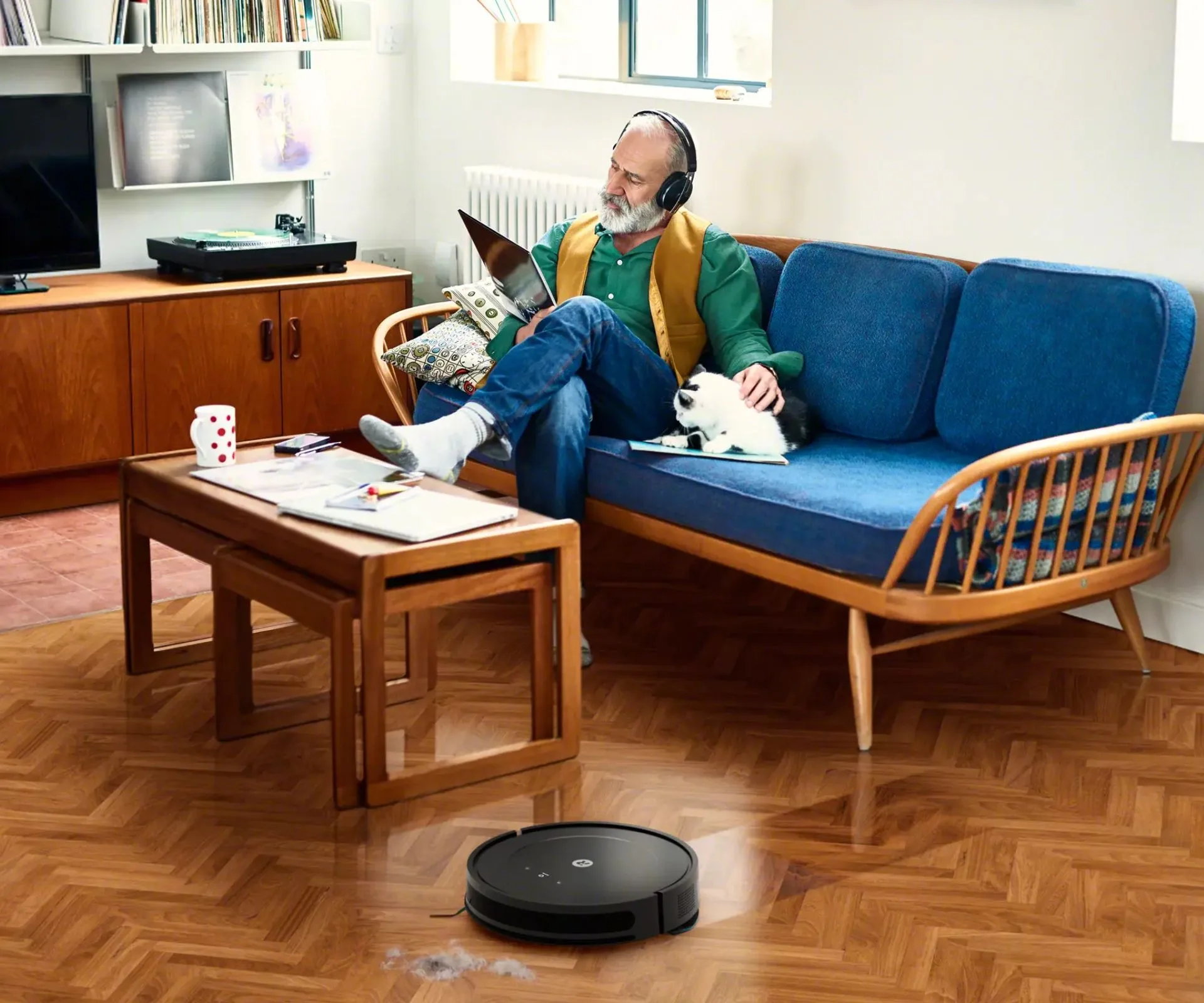 iRobot Roomba vacuuming beside a man listening to music