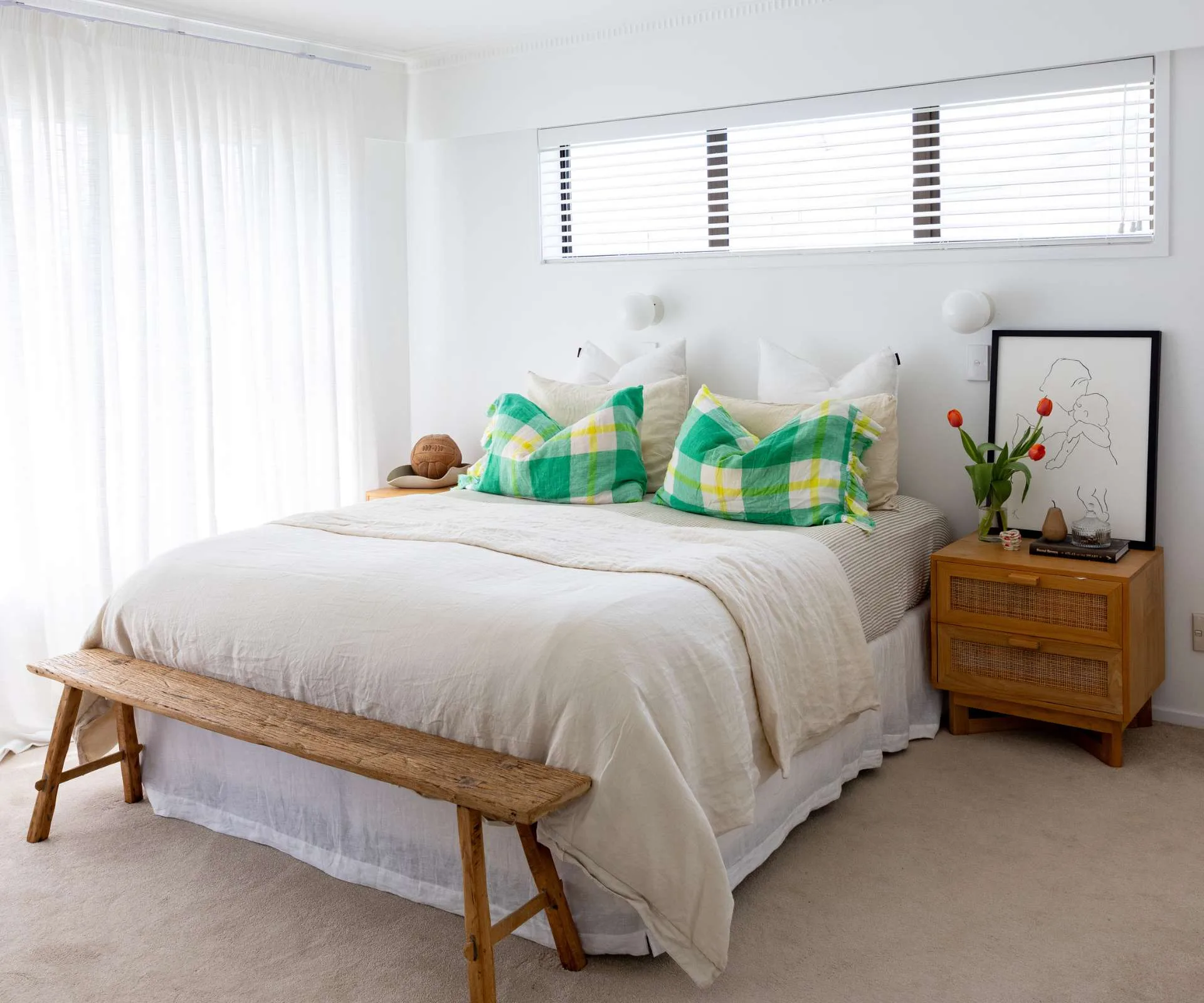 A plain white master bedroom with green cushions on the bed