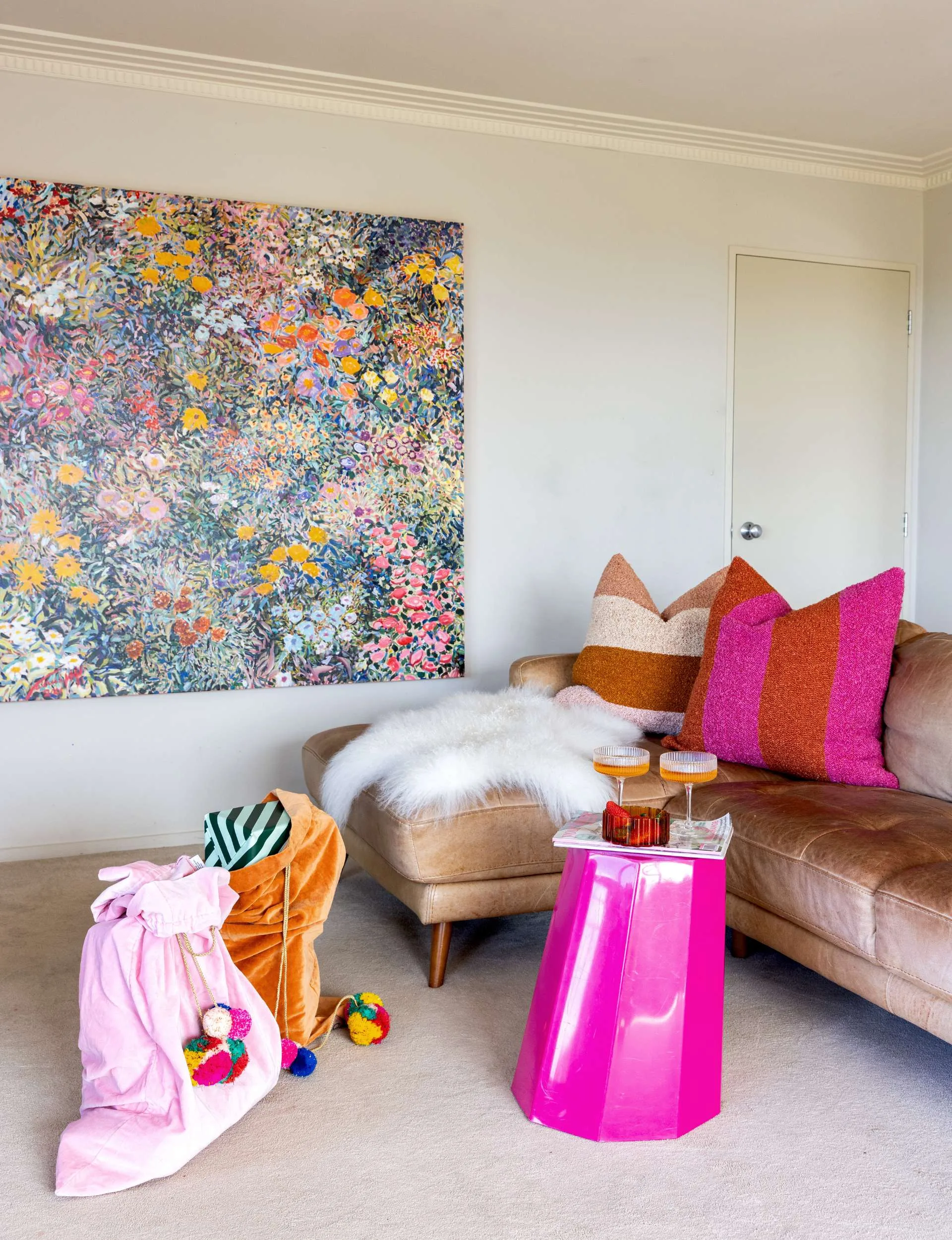 The Whangaparāoa home living room with a brown leather couch and a pink circus stool