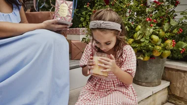 A little girl holding a Circa Christmas candle