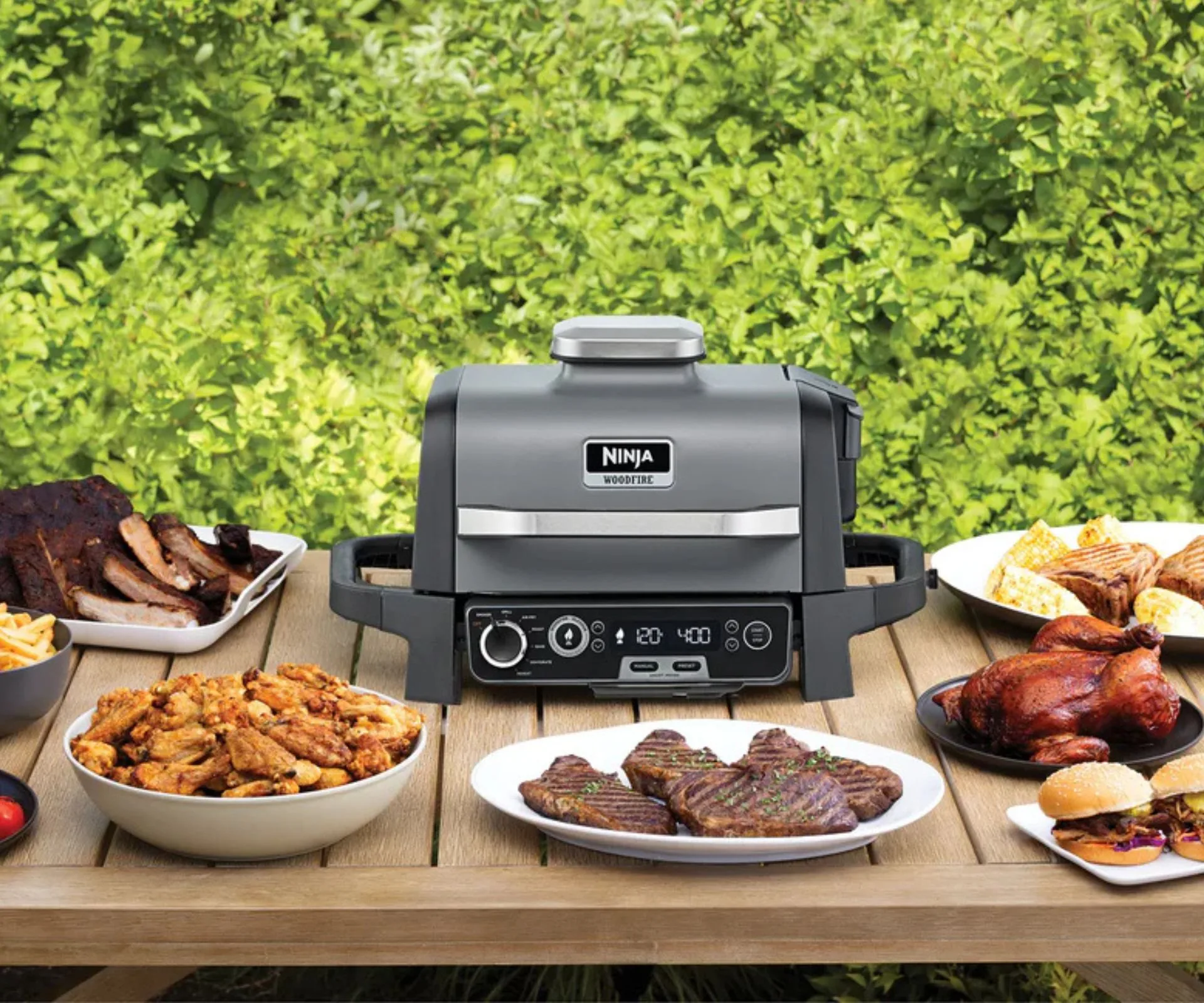 Ninja Woodfire surrounded by barbequed food