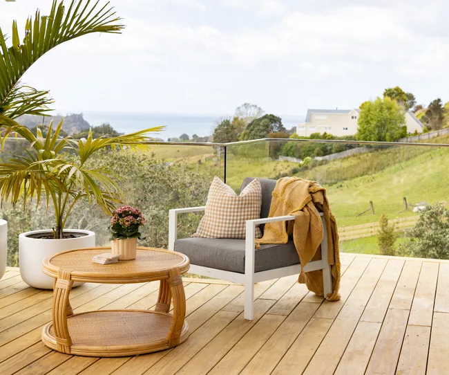 Outdoor deck with outdoor chair and coffee table. With mustard cushion and blanket