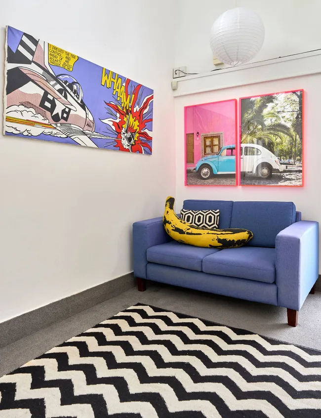 A purple couch sits near a black and white zig-zag rug in the Auckland art deco home