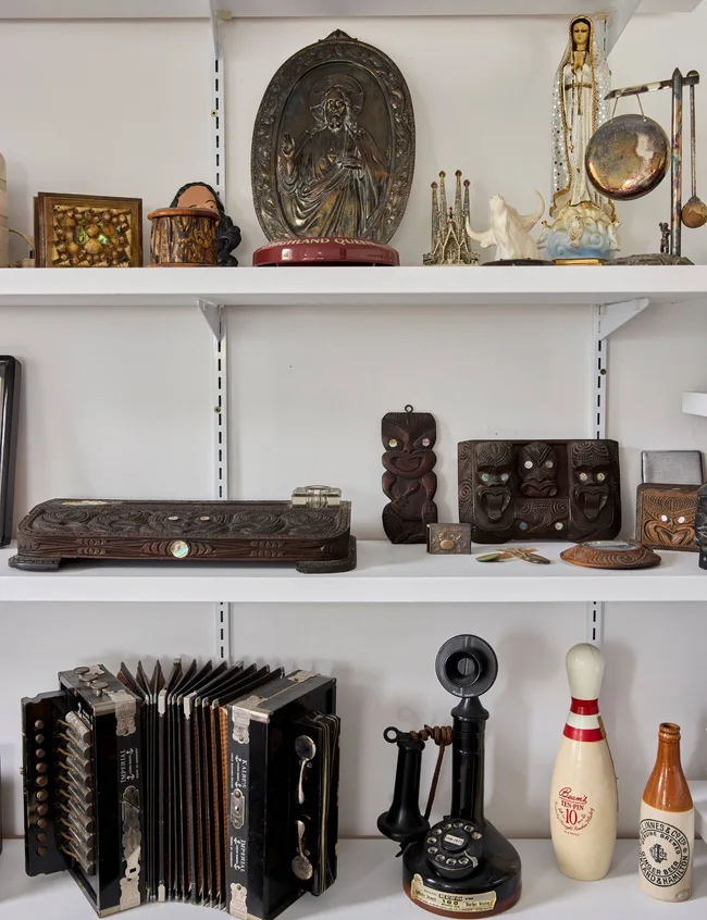 A shelf covered in dark coloured decor and trinkets