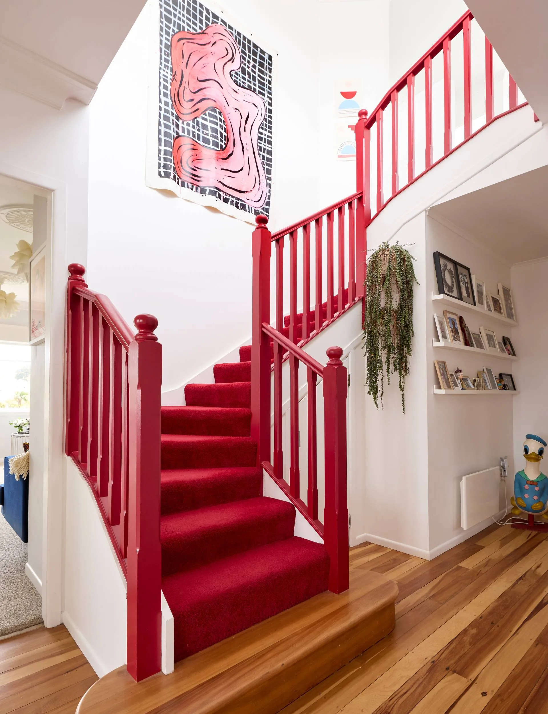 A bright red staircase stands in the middle of the Auckland art deco home