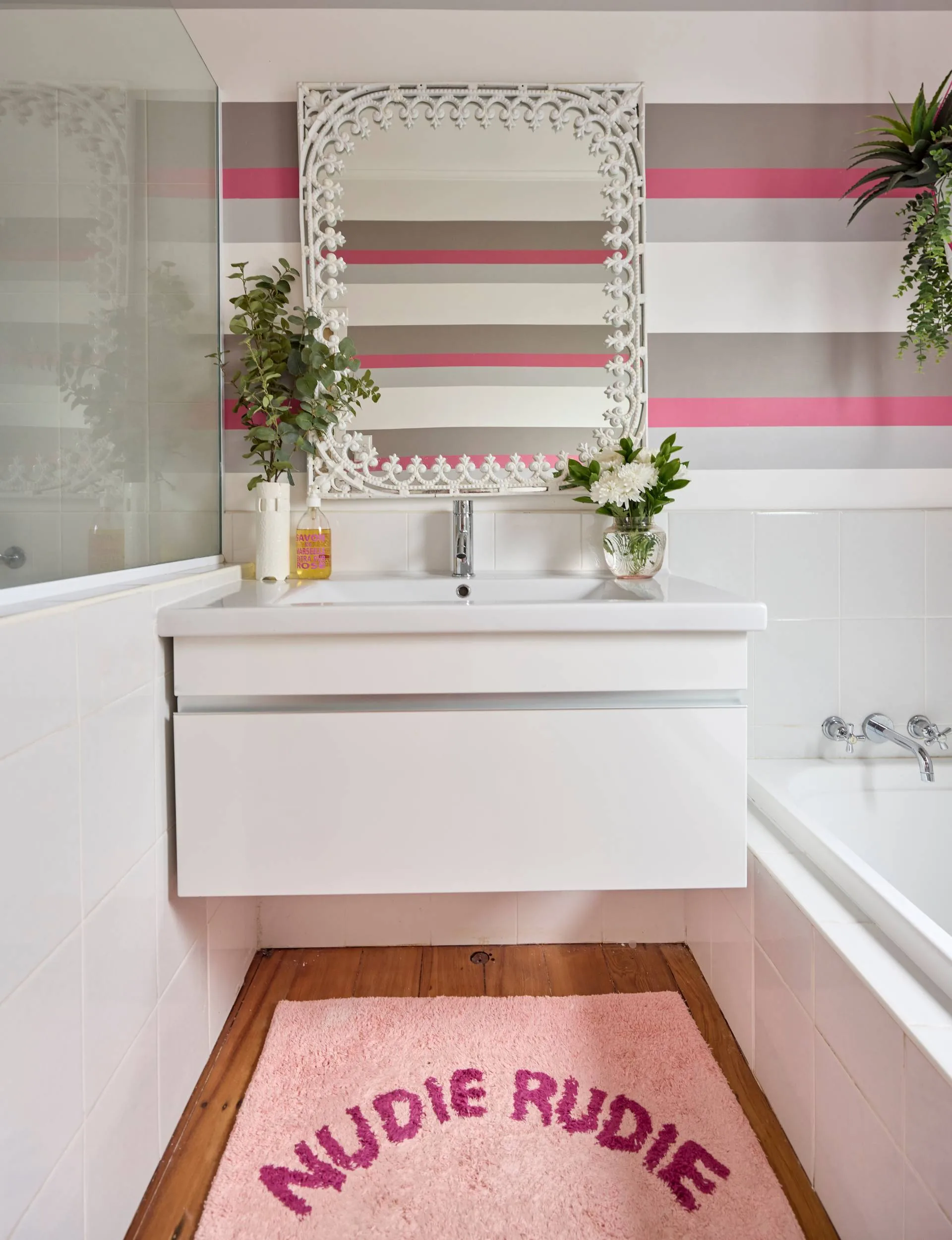 The bathroom of the Auckland art deco home has pink, grey and white striped wallpaper