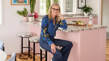 Homeowner Erina sitting in the pink kitchen of her Auckland art deco home