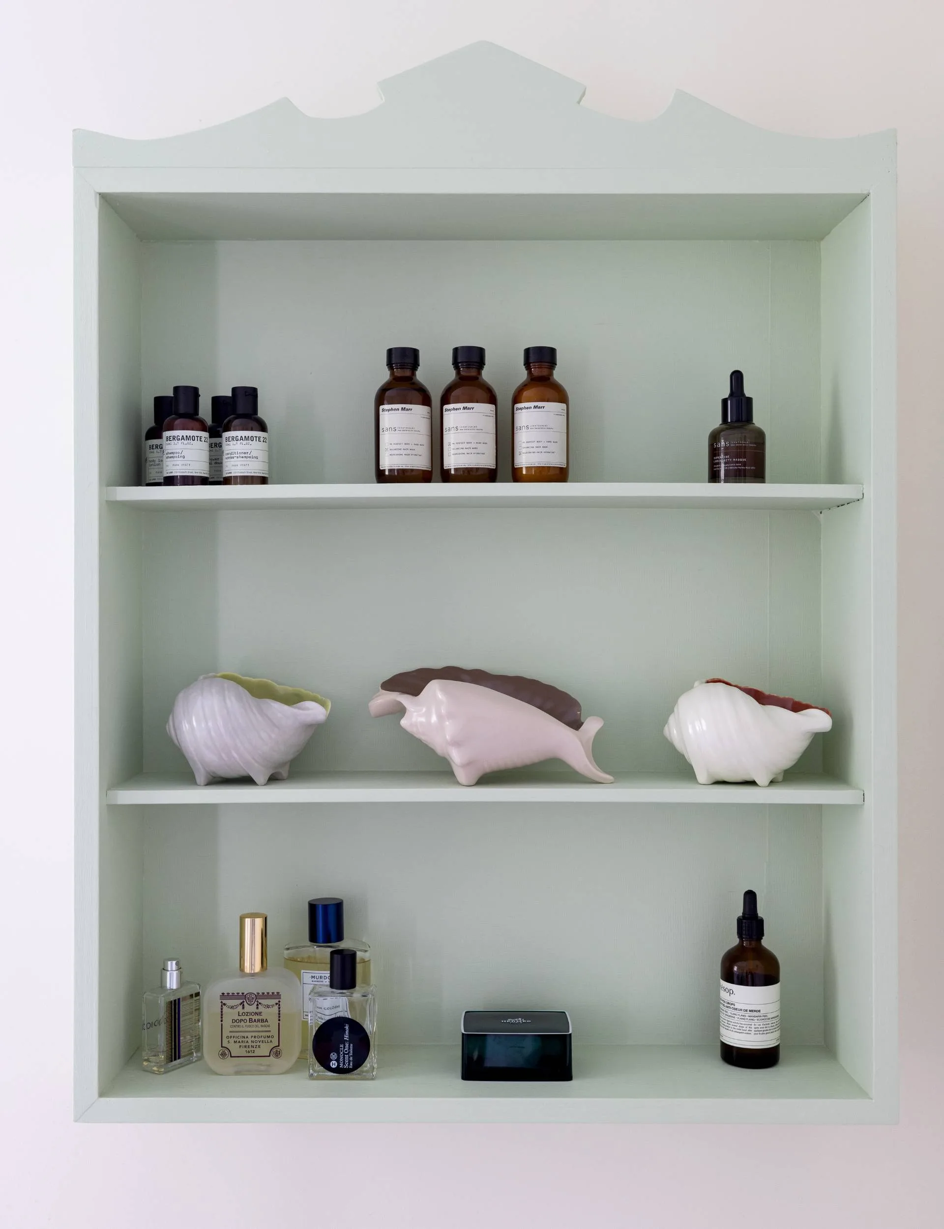 A sea foam green shelving unit mounted to a white wall in the Point Wells bach