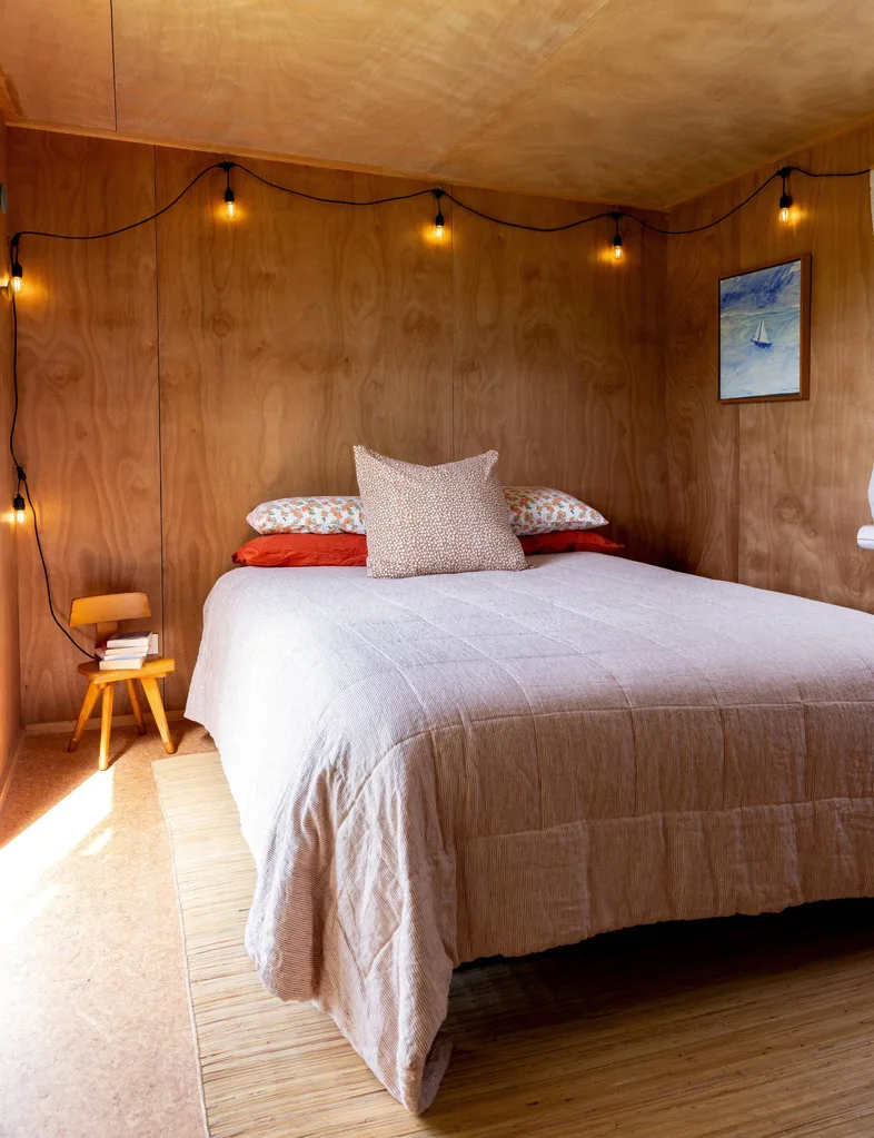 A wooden bedroom with a white double bed in the corner