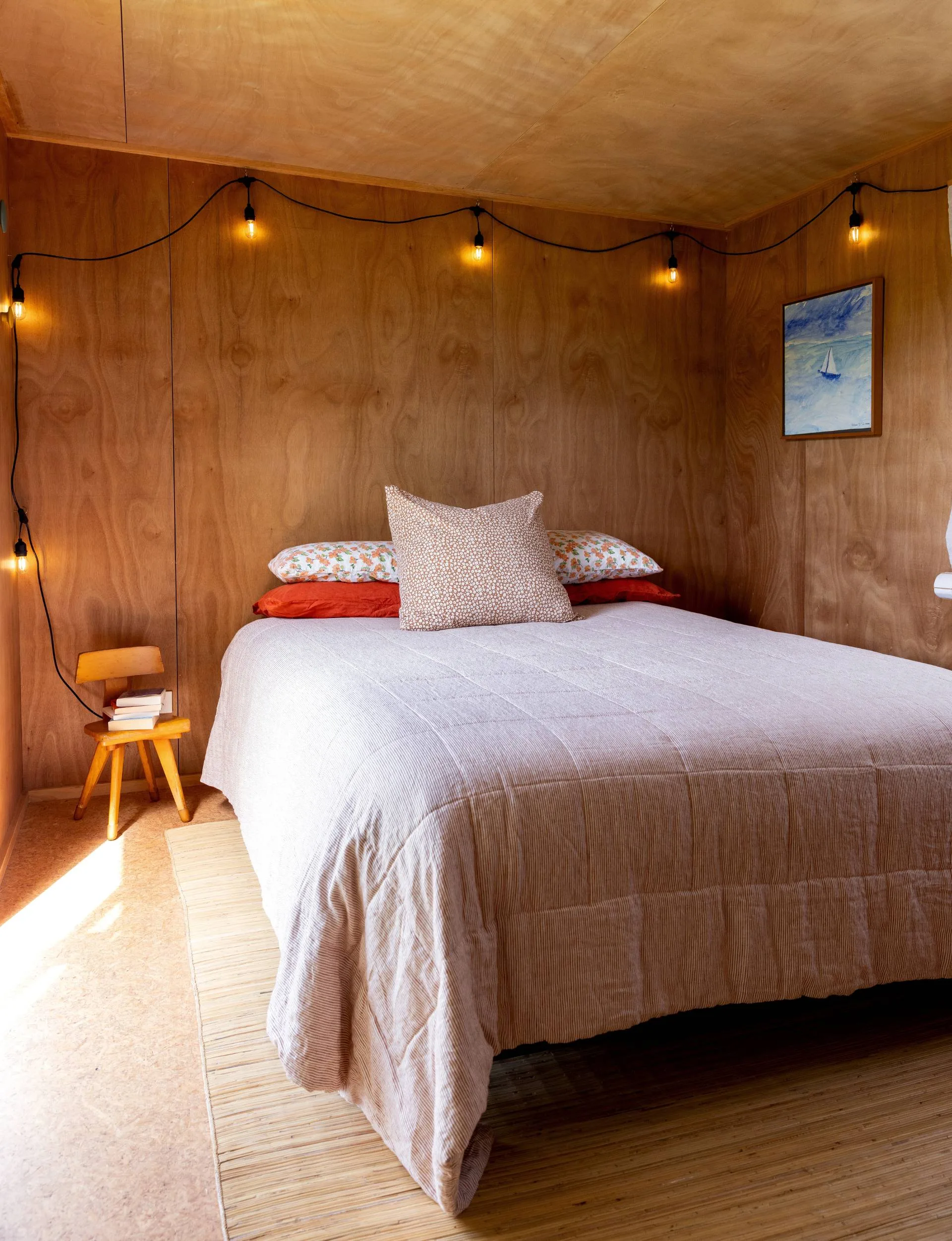 A wooden bedroom with a white double bed in the corner