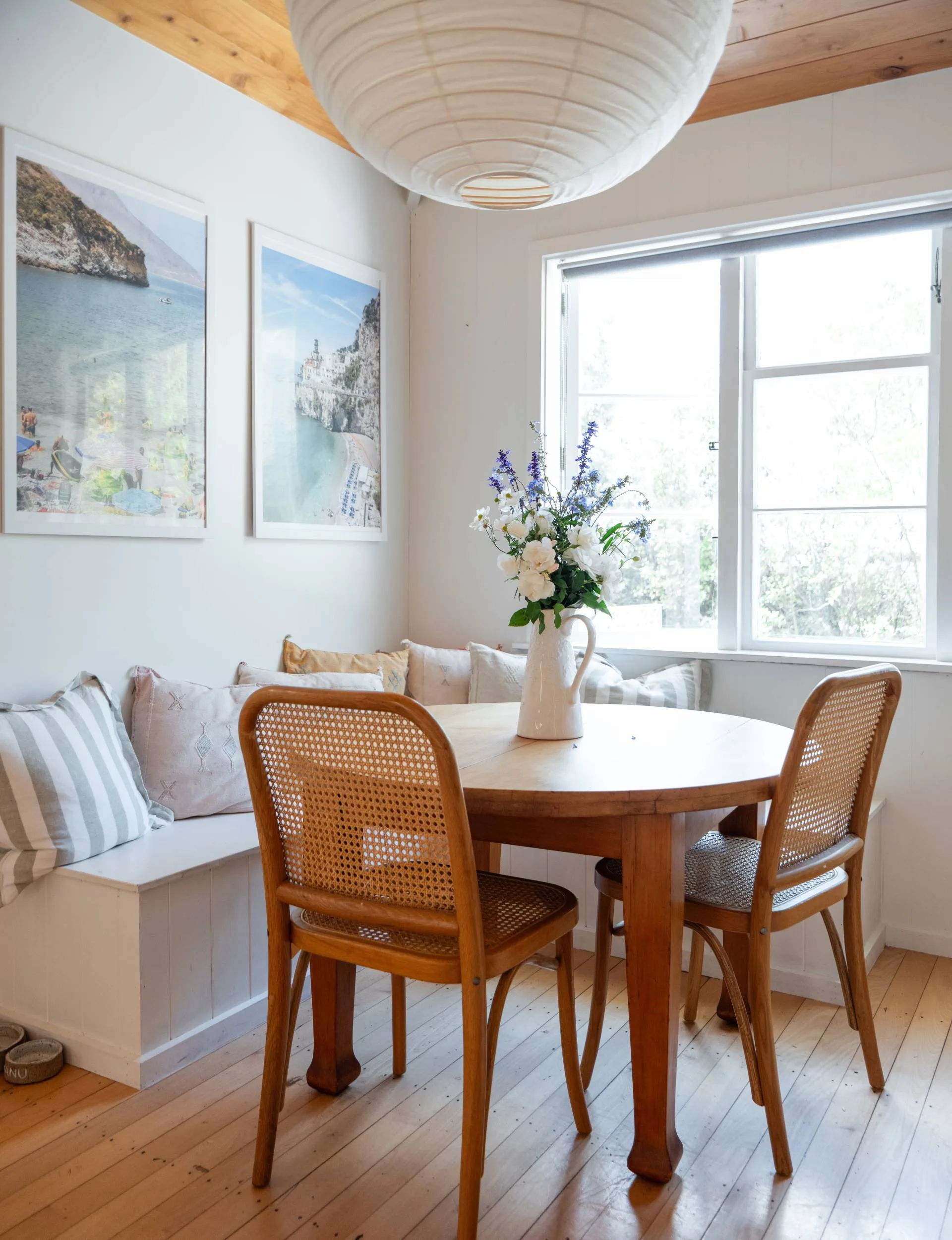 A round dining room table against a window seat