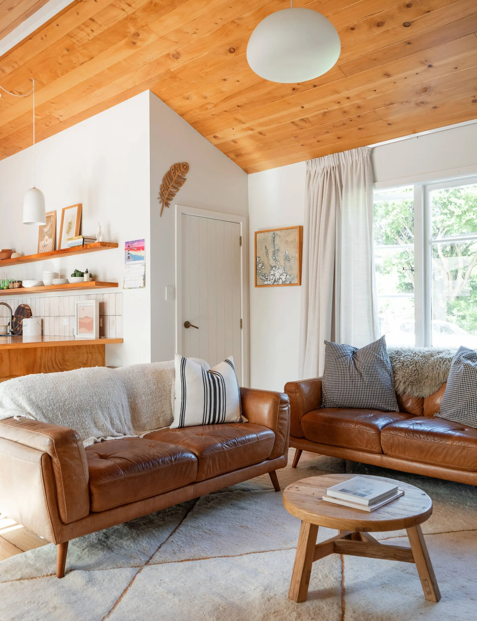 The Wainui Beach bungalow living room with brown leather couches