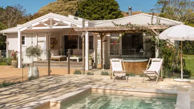 The exterior of the Wainui Beach bungalow with the pool in the foreground