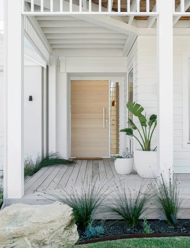 The Hamptons-style front door is made of light coloured wooden horizontal planks