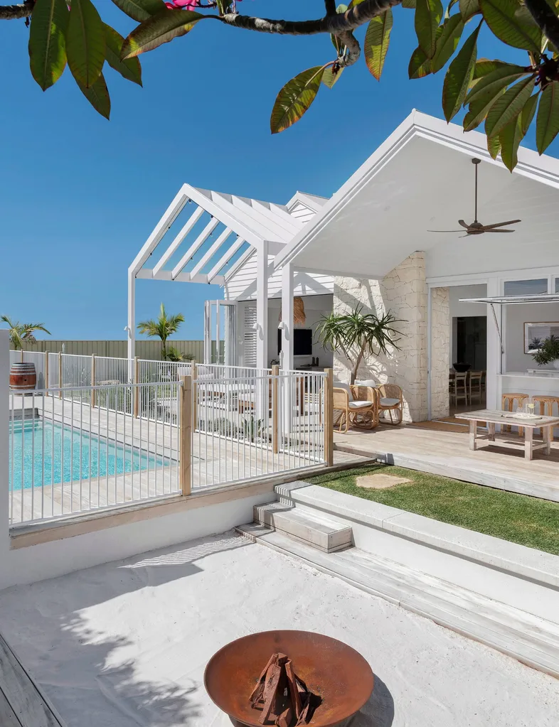 The back exterior of the Hamptons-style home with the pool and outdoor entertaining area