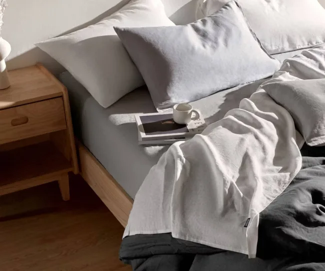 A bed made with grey, linen sheets