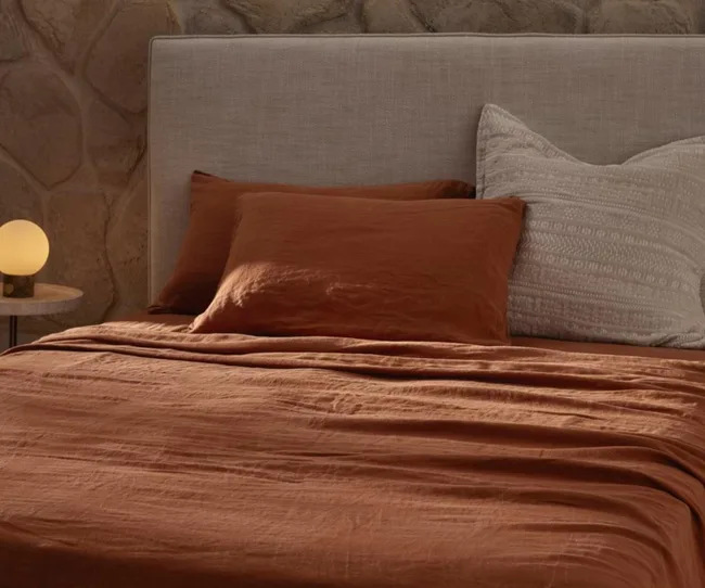 Terracotta coloured linen sheets on a bed with two pillows