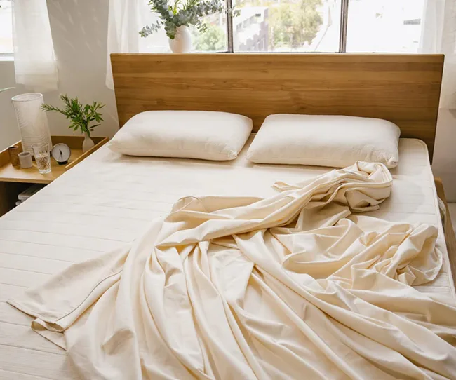 Light coloured sheets on an unmade bed