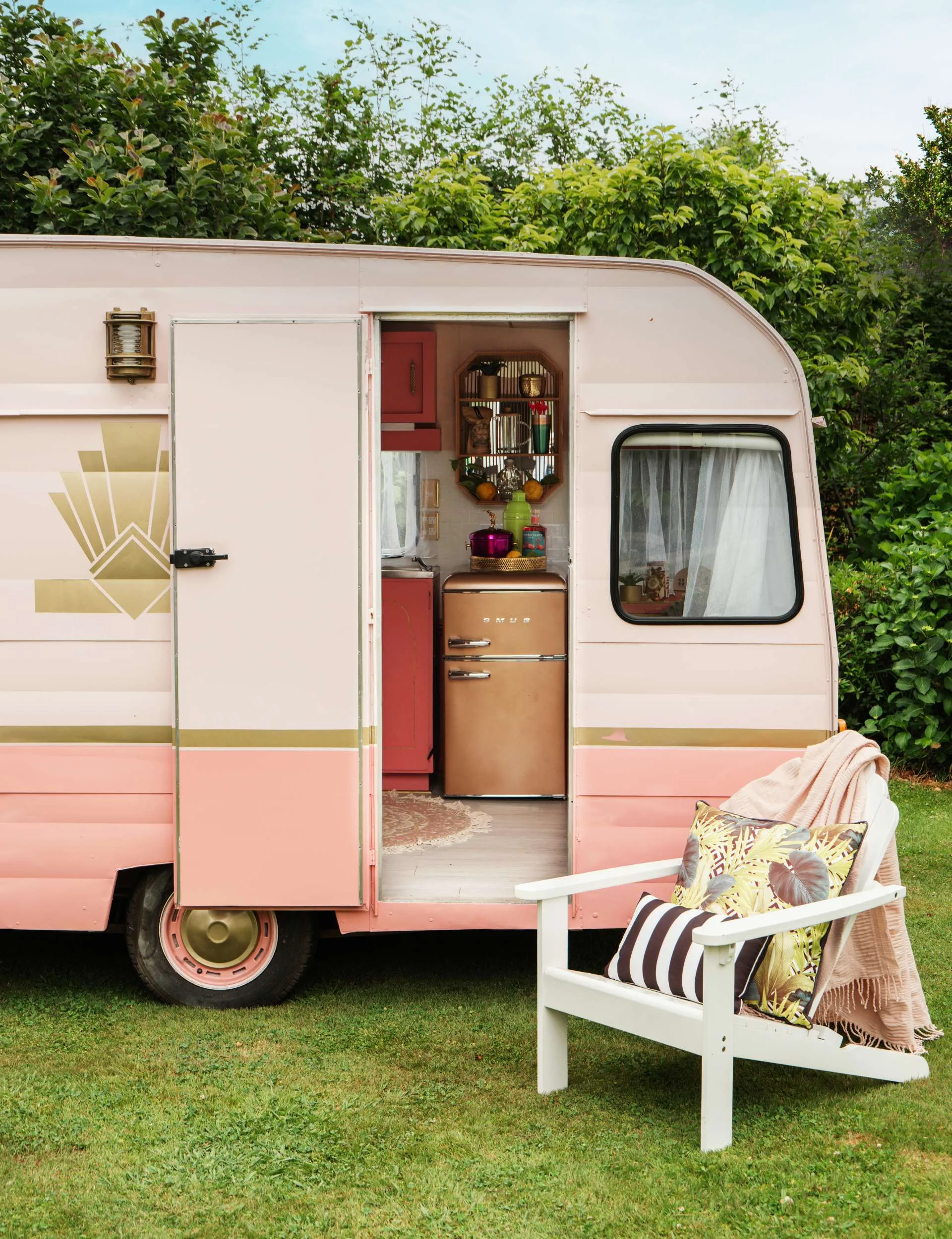 pink caravan with chair in front of it