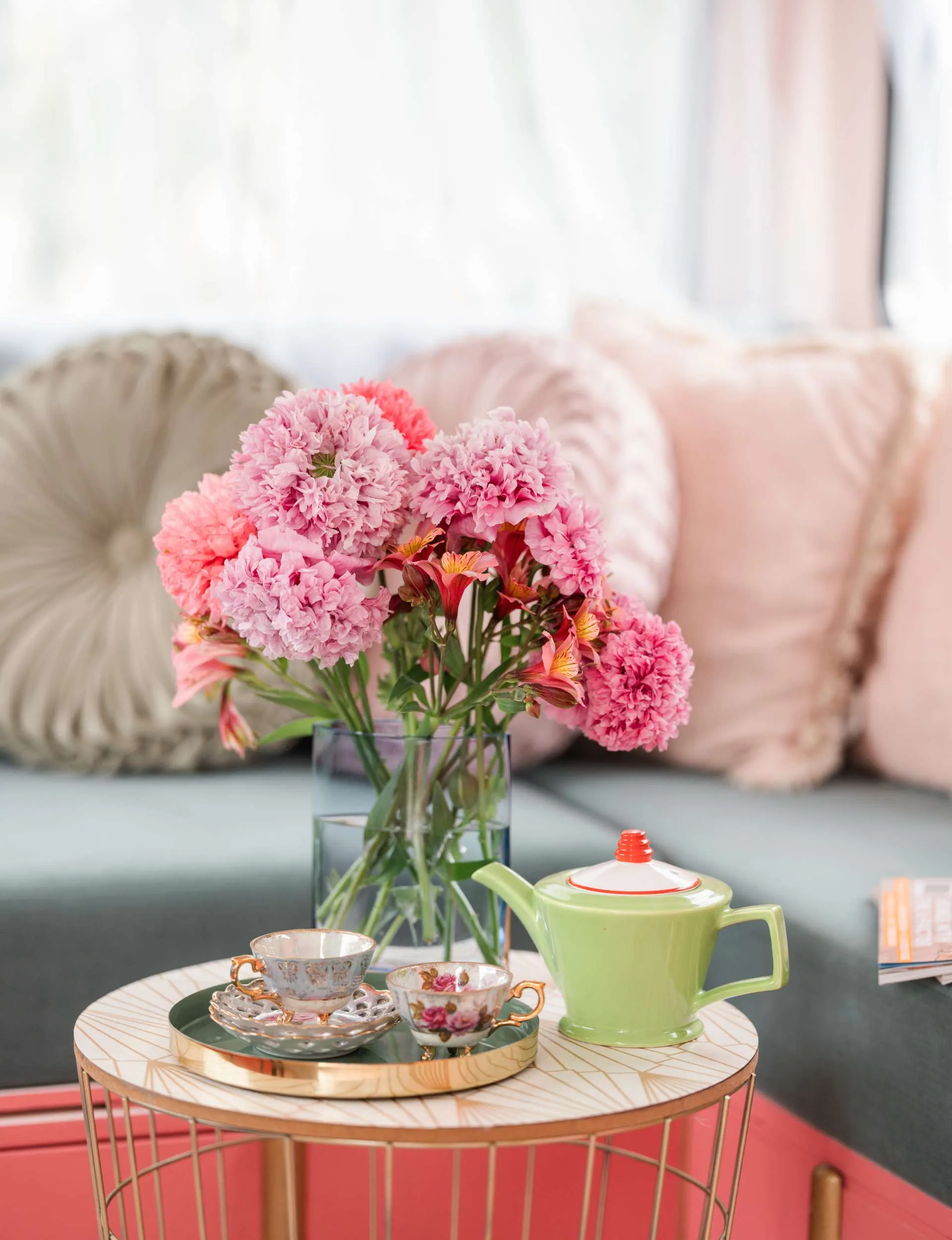 pink flowers on coffee table with a tea cup and tea pot