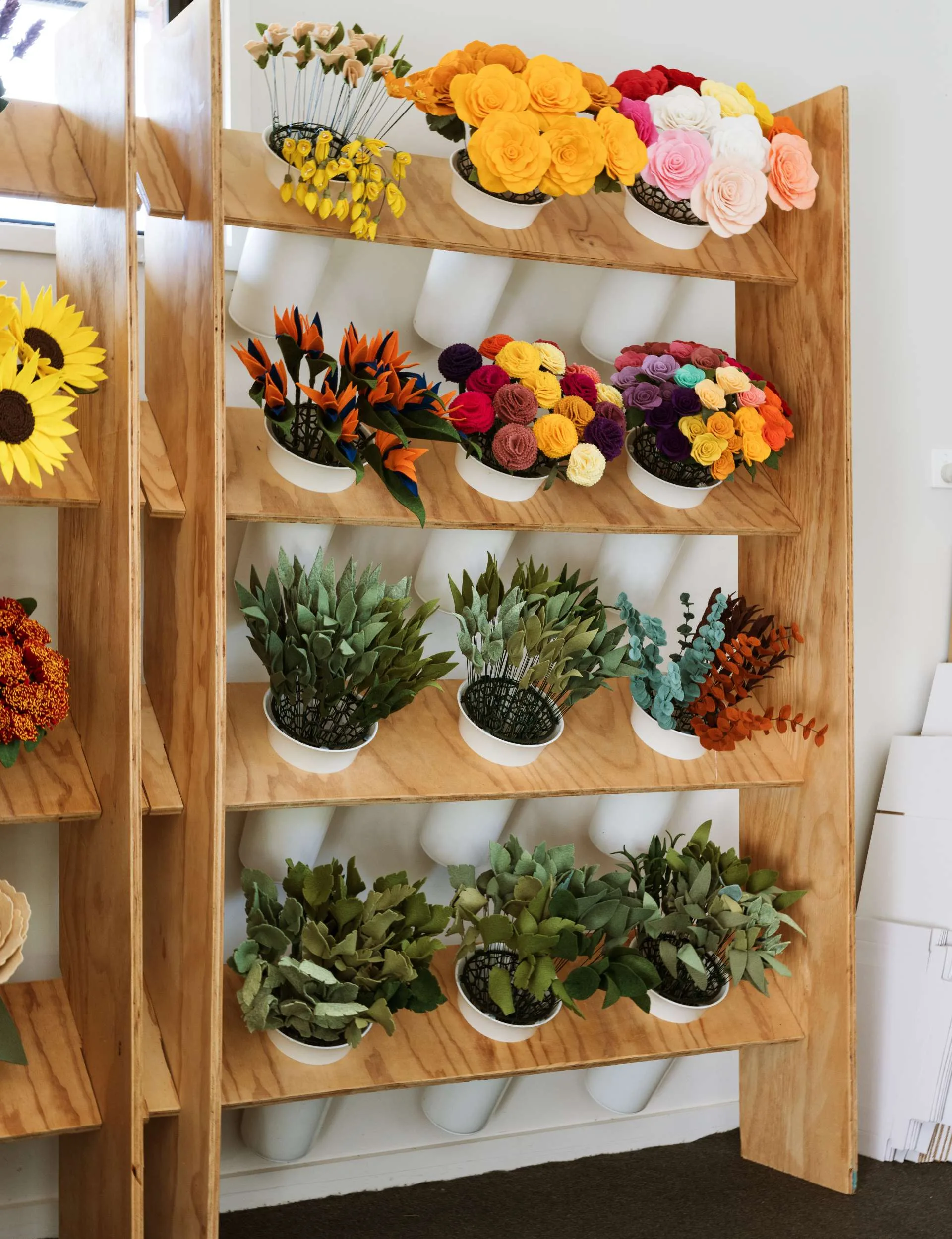 12 bouquet of felt flowers are displayed on a shelf