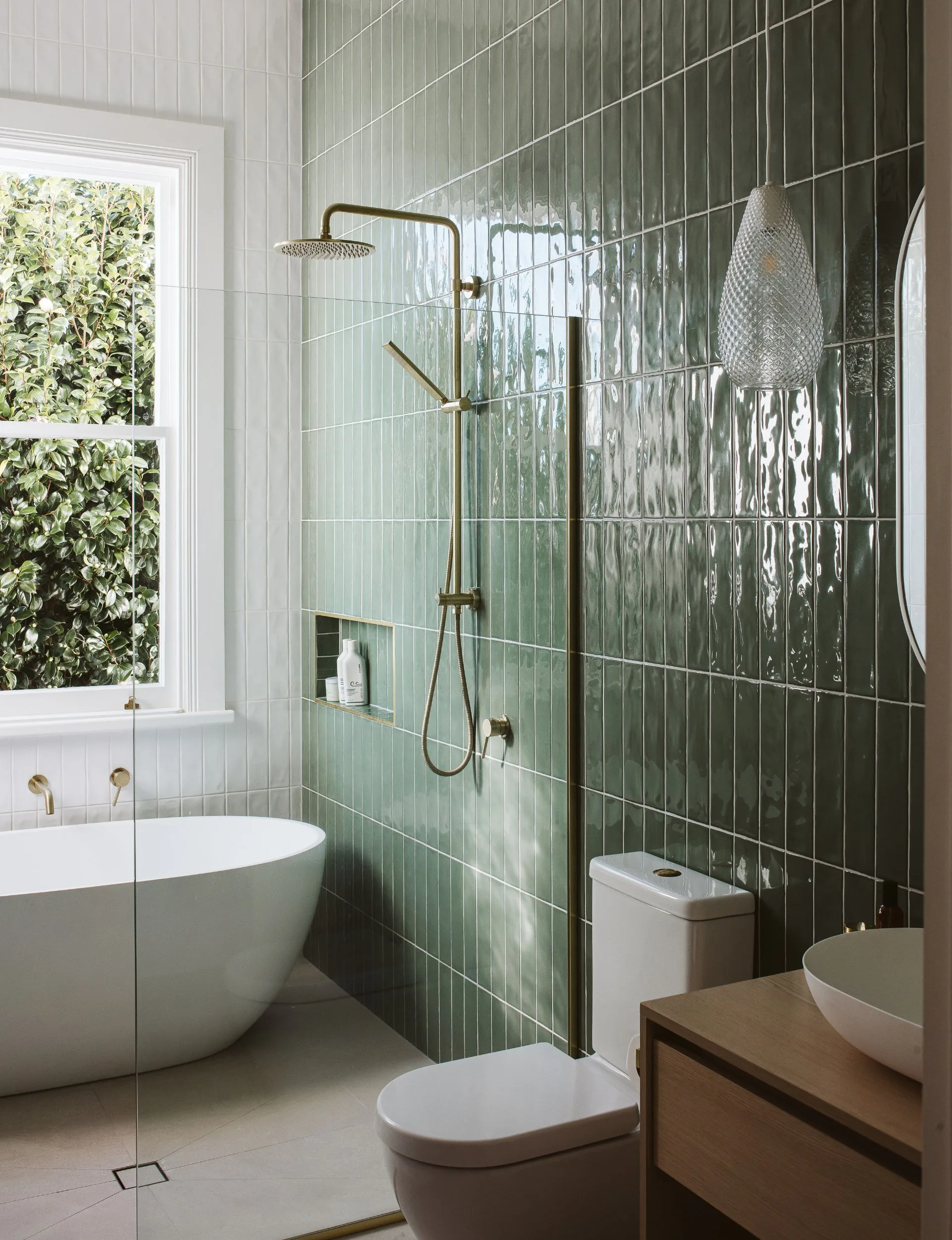 The bathroom has an oval white bath with a feature wall of deep green tiles
