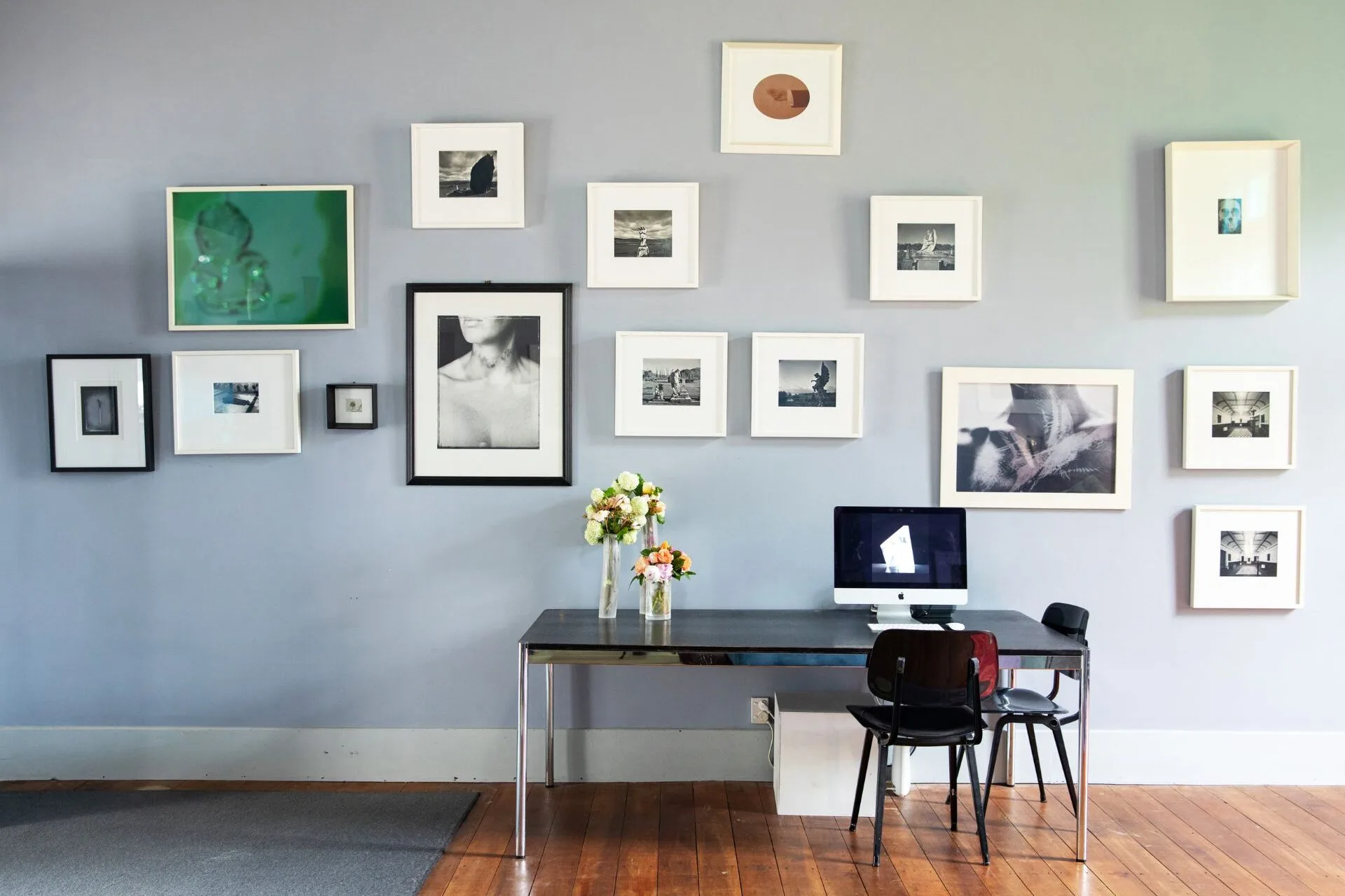 A desk in front of a wall covered in framed art