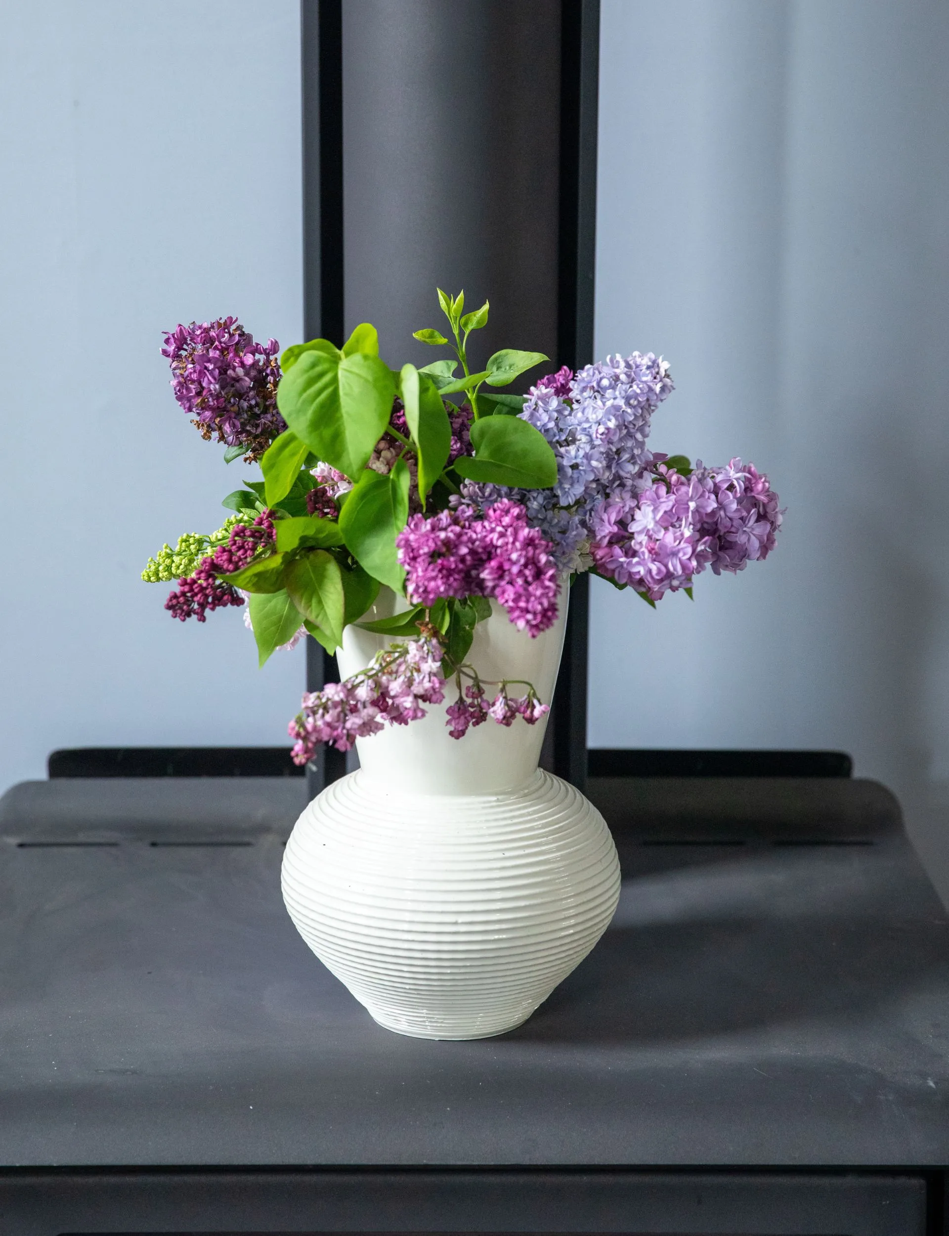 A vase of hydrangeas on top of the fireplace