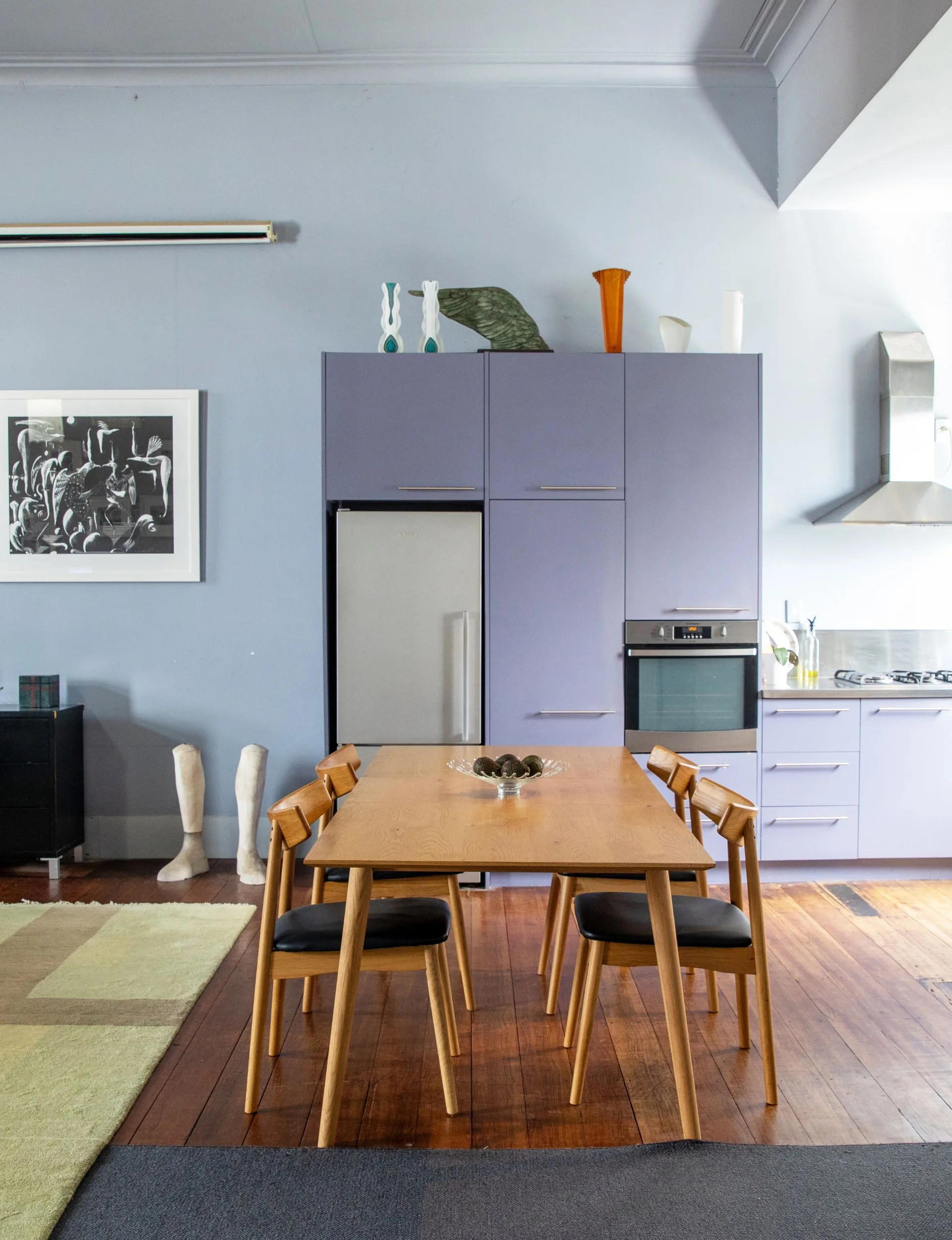 The lilac kitchen behind a wooden dining room table