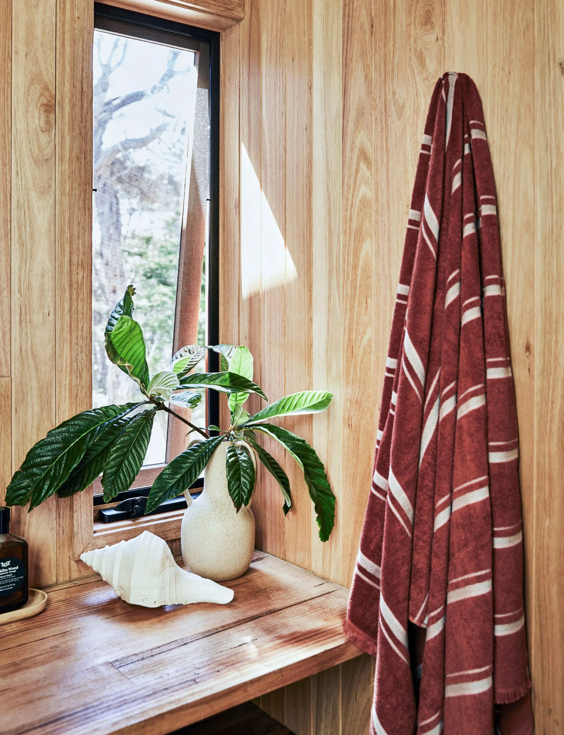 A red and white striped towel hanging beside a bench in the renovated beach cabin bathroom