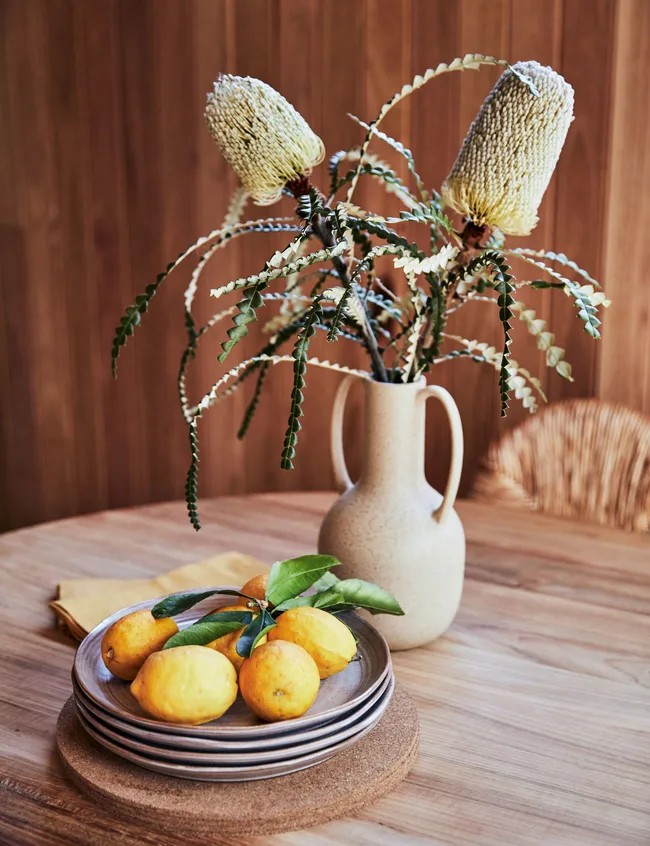 A vase and bowl of lemons on the dining room table