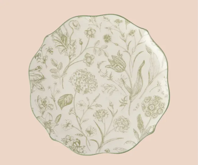 A green floral dinner plate against a pink background