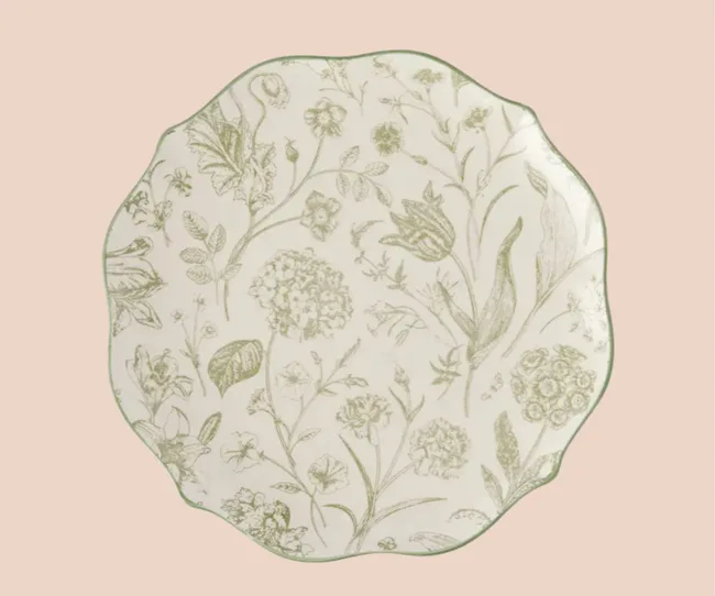 A green floral dinner plate against a pink background