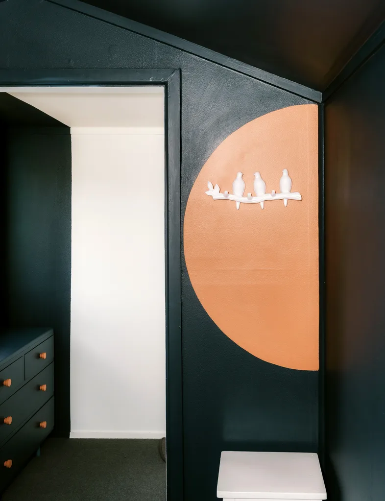 Dark green wall with a half circle featured painted in orange
