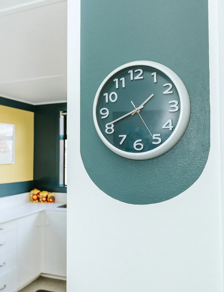 A lighter blue green wall with a darker blue green accent circle perfectly matches the clock