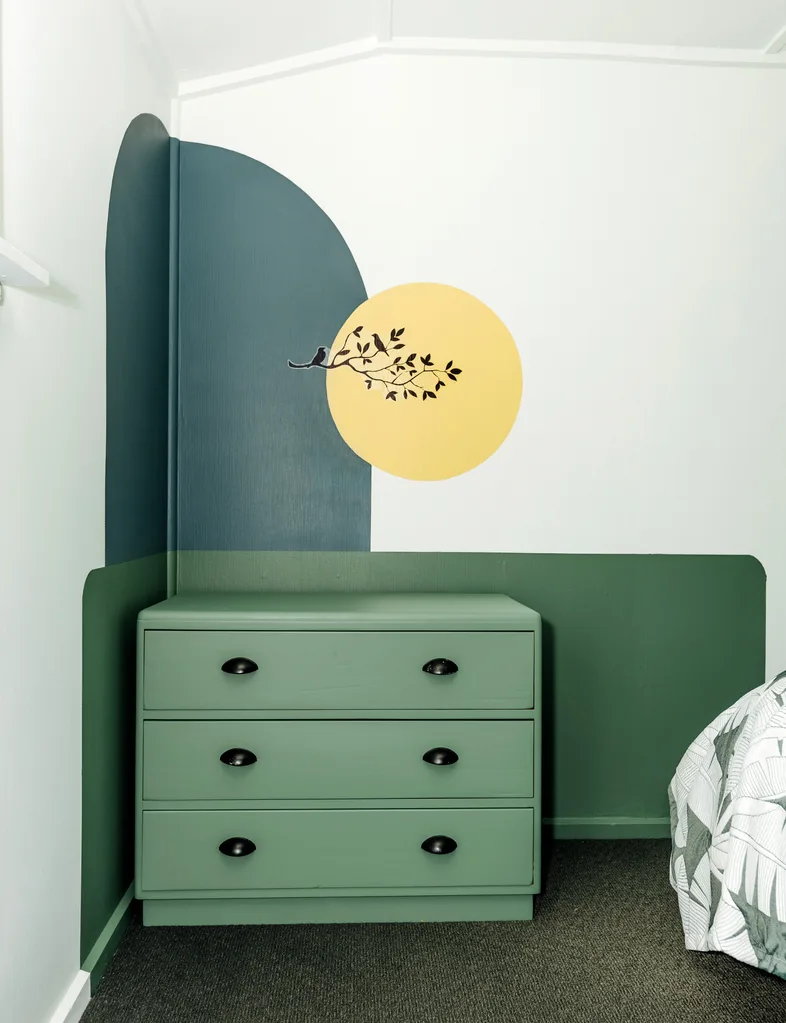 A feature wall in one of the bedrooms uses a green, dark blue-green and yellow paint
