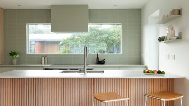 A kitchen with an oak island and an olive green backsplash