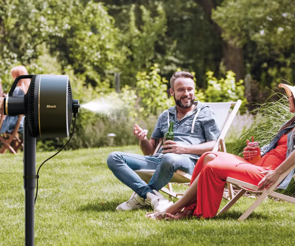 A man having a beer under the mist of the Shark FlexBreeze Fan