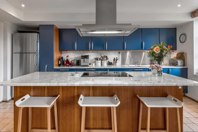 The blue kitchen with barstools in the foreground
