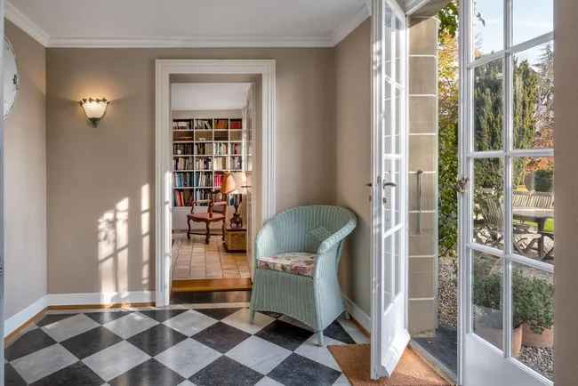 An entranceway with a blue armchair and checked flooring