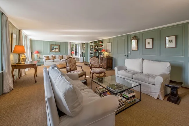 A living room with blue walls and two white sofas facing each other