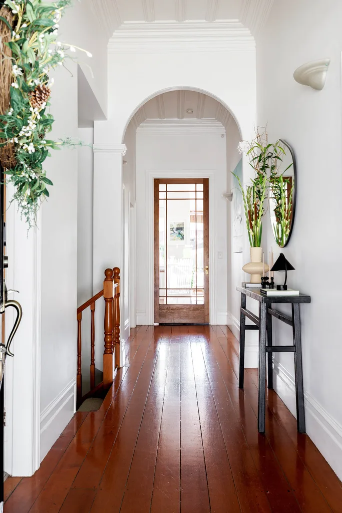 A hallway with white walls and wooden floors.