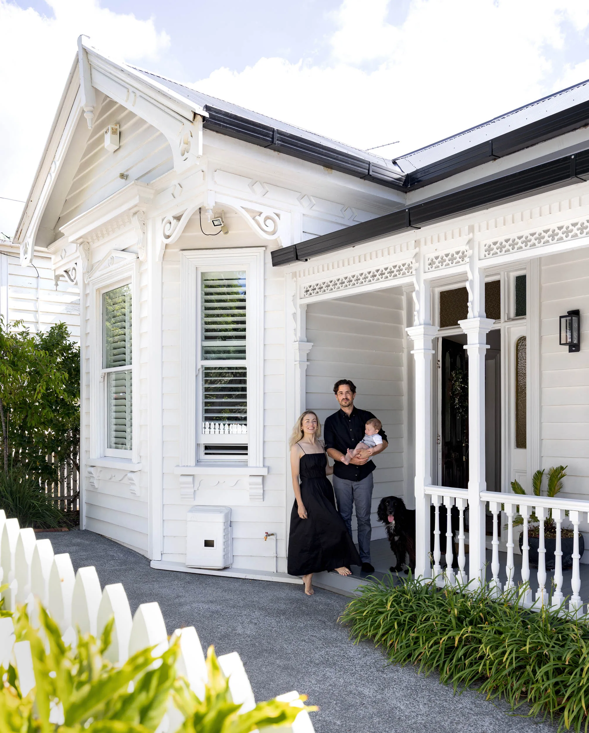 A man and a woman standing on the front porch of a white villa. 
