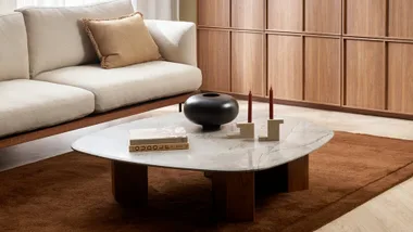 A cinnamon coloured rug with a marble coffee table and white sofa.